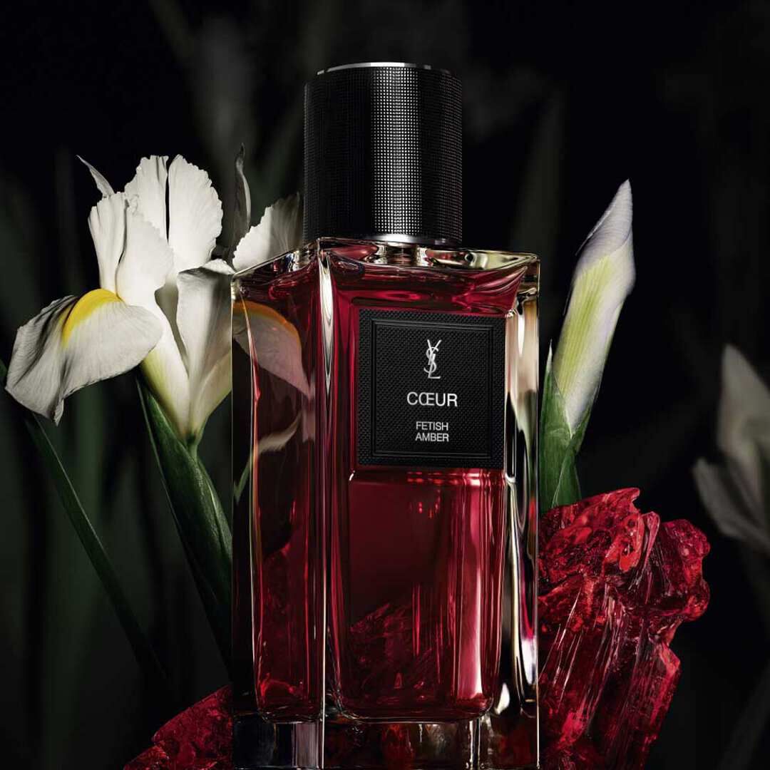 Flacon de parfum YSL Coeur Fetish Amber avec fleurs d’iris blanches et accents de cristal rouge.