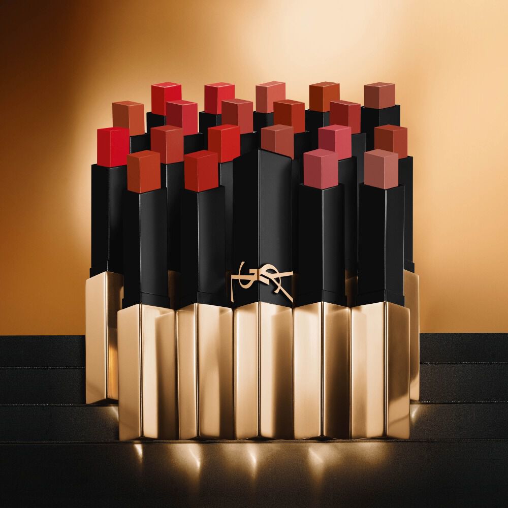 Mehrere schmale quadratische Lippenstifte von Yves Saint Laurent in verschiedenen Rot- und Nudetonen auf goldenem Hintergrund.