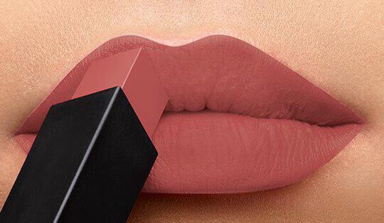 Close-up of lips being touched by a nude lipstick bullet.