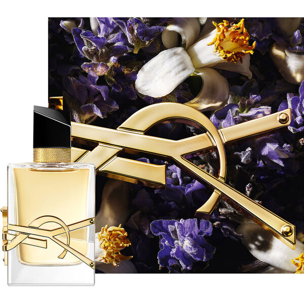 Flacon Libre Eau de Parfum orne d’une chaine doree et de fleurs violettes sur fond sombre.