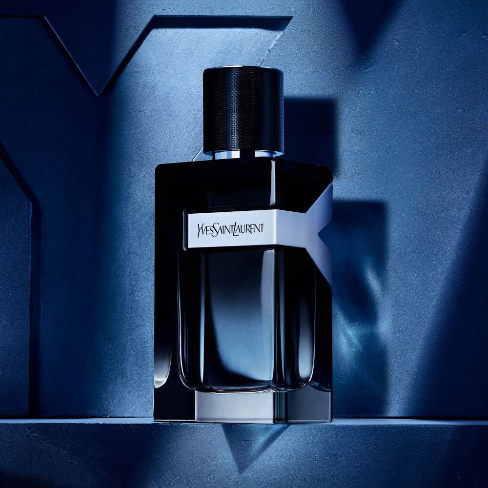 A sleek, black perfume bottle with a modern design, featuring the label "Yves Saint Laurent," displayed against a dark, textured background.