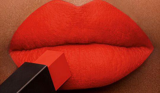 Close-up of bold red lips with a lipstick application in progress, showcasing a striking and glossy finish.