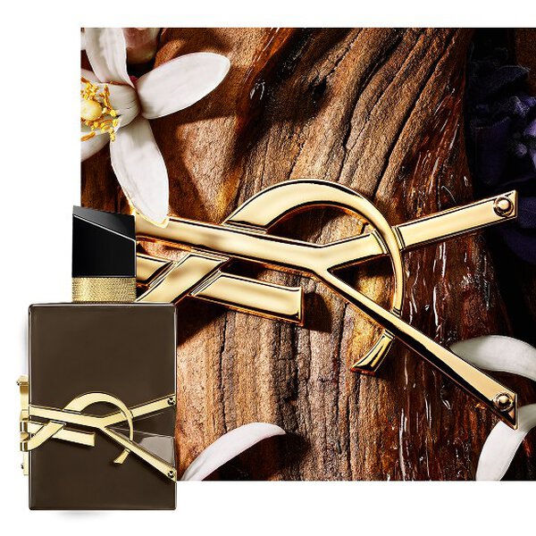 Flacon brun glace Libre Santal Couture sur ecorce de santal, orne de la Cassandre doree et de fleurs blanches.