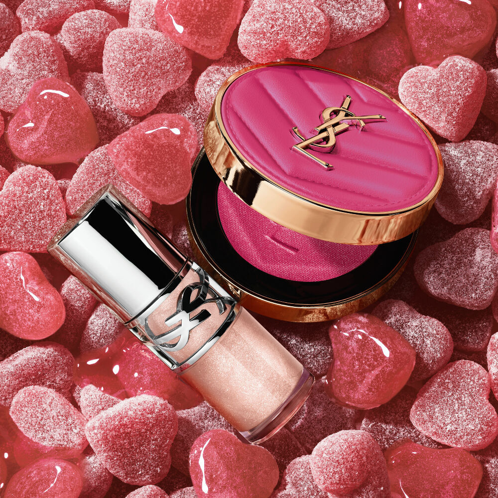 YSL LOVESHINE Plumping Lip Oil Gloss Farbton 10 und Make Me Blush Farbton 66, inmitten von leuchtend rosa herzformigen Sußigkeiten.