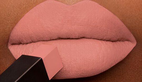 Close-up of smooth, soft lips being applied with a nude lipstick.