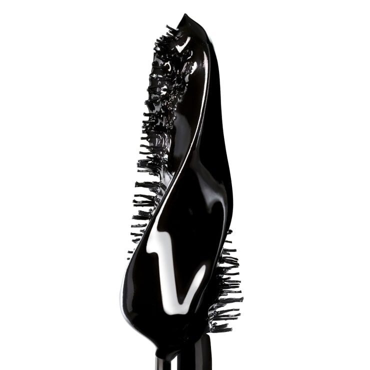A close-up image of a black mascara wand with a unique, twisted bristle design. The wand is coated in glossy black product.
