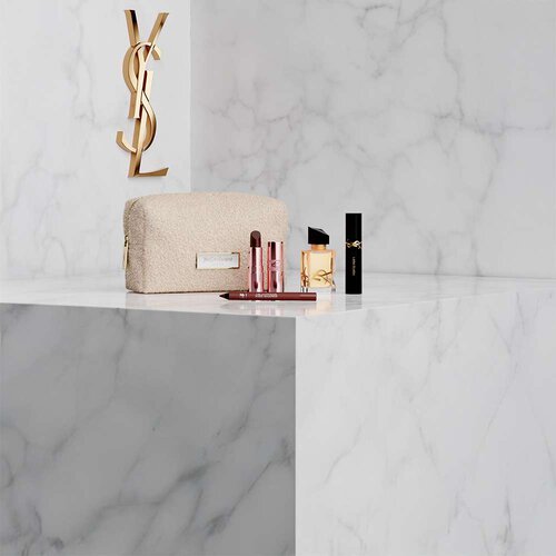 Kosmetiktasche, Libre Parfum und YSL Make-up auf weißem Marmorhintergrund.