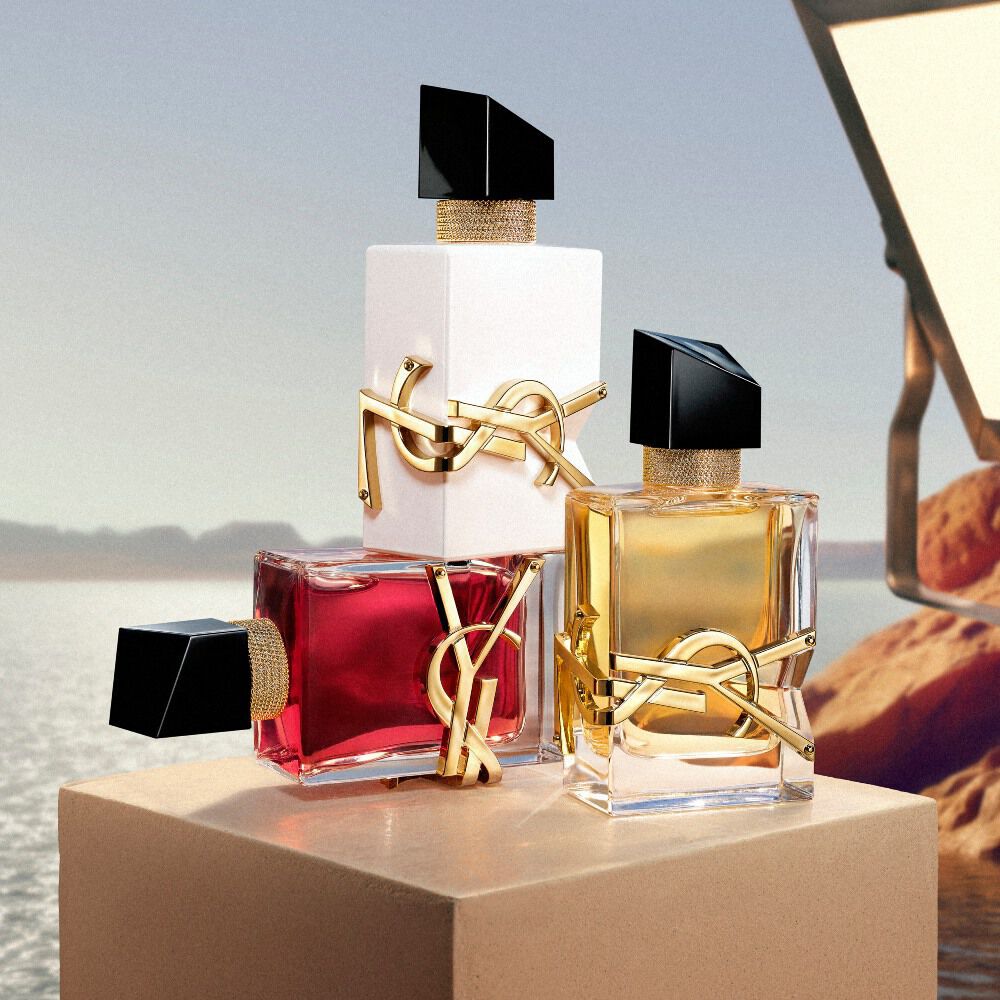 Flacons de parfum YSL disposes sur un piedestal devant un paysage desertique.