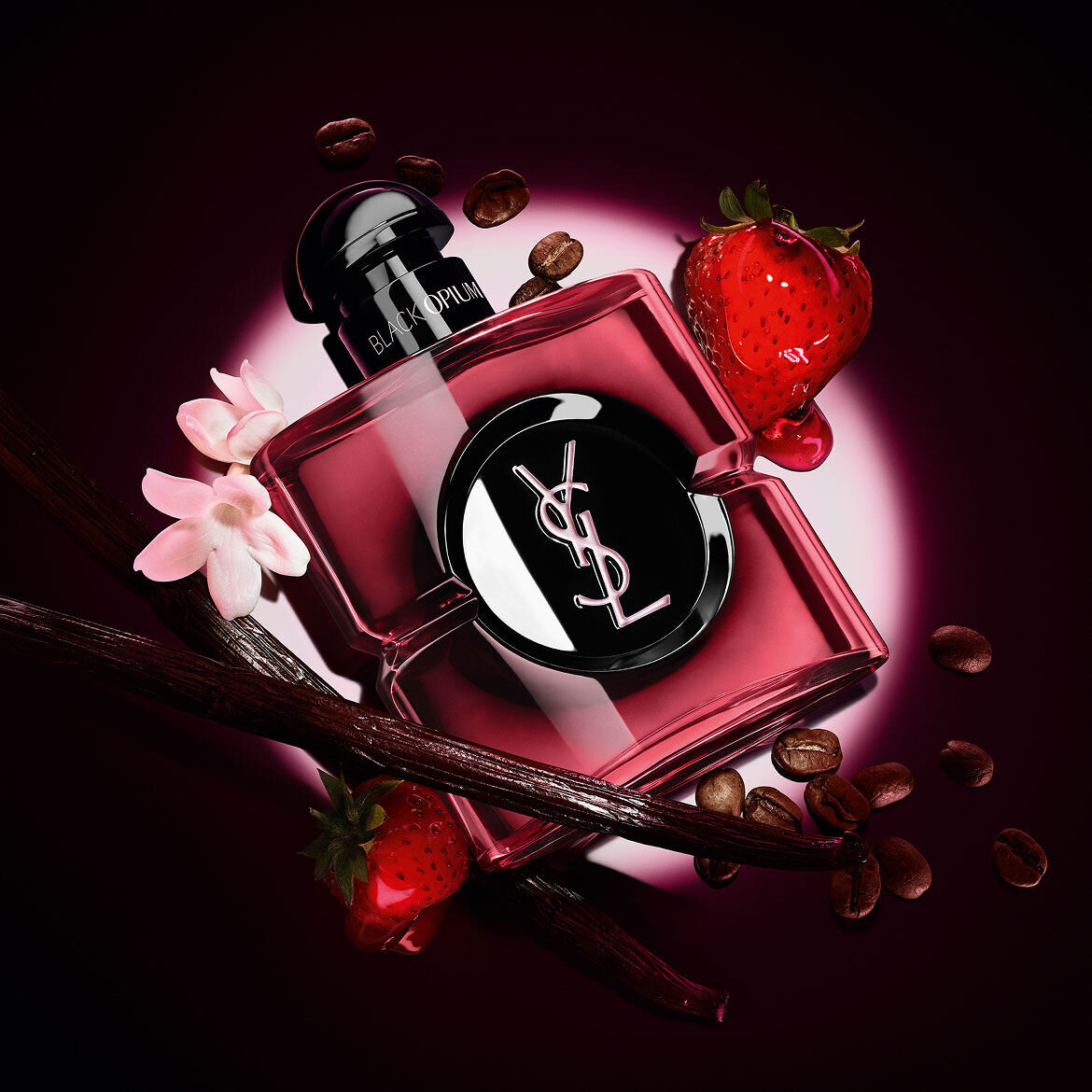 Flacon Black Opium Eau de Parfum Pink Glaze entoure de fraises fraiches, de gousses de vanille, de grains de cafe et de jasmin.