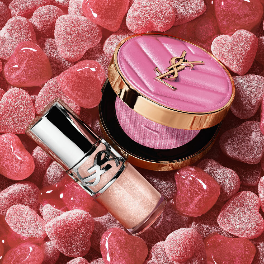YSL LOVESHINE Plumping Lip Oil Gloss Farbton 10 und Make Me Blush Farbton 10, umgeben von rosa herzformigen Sußigkeiten.