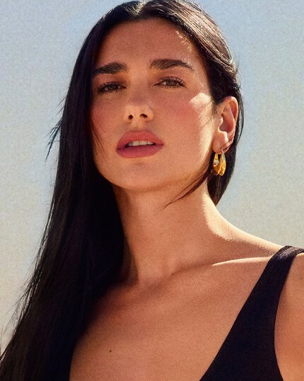 Dua Lipa, ambassadrice YSL Beauty, au regard intense face a l’objectif, dans un decor desertique, les cheveux bruns ondoyants et un tatouage discret.