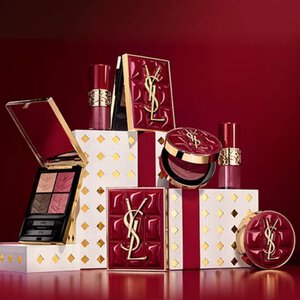 Coffrets cadeaux de la collection de fetes Yves Saint Laurent et produits de beaute de luxe sur fond rouge festif.