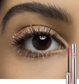 Close-up of a woman's eye showcasing long, defined eyelashes, with a mascara tube positioned beside it. The eye is dark brown, and the makeup has a natural look.