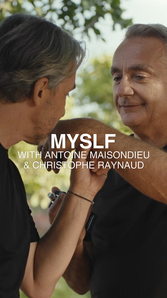 Deux hommes en t-shirt noir interagissent en plein air, l'un tenant le bras de l'autre et un petit objet. L'image est recouverte du texte "MYSLF WITH ANTOINE MAISONDIEU & CHRISTOPHE RAYNAUD" sur un fond flou de feuillage vert.