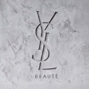 In eine strukturierte graue Betonwand graviertes YSL BEAUTE Logo.