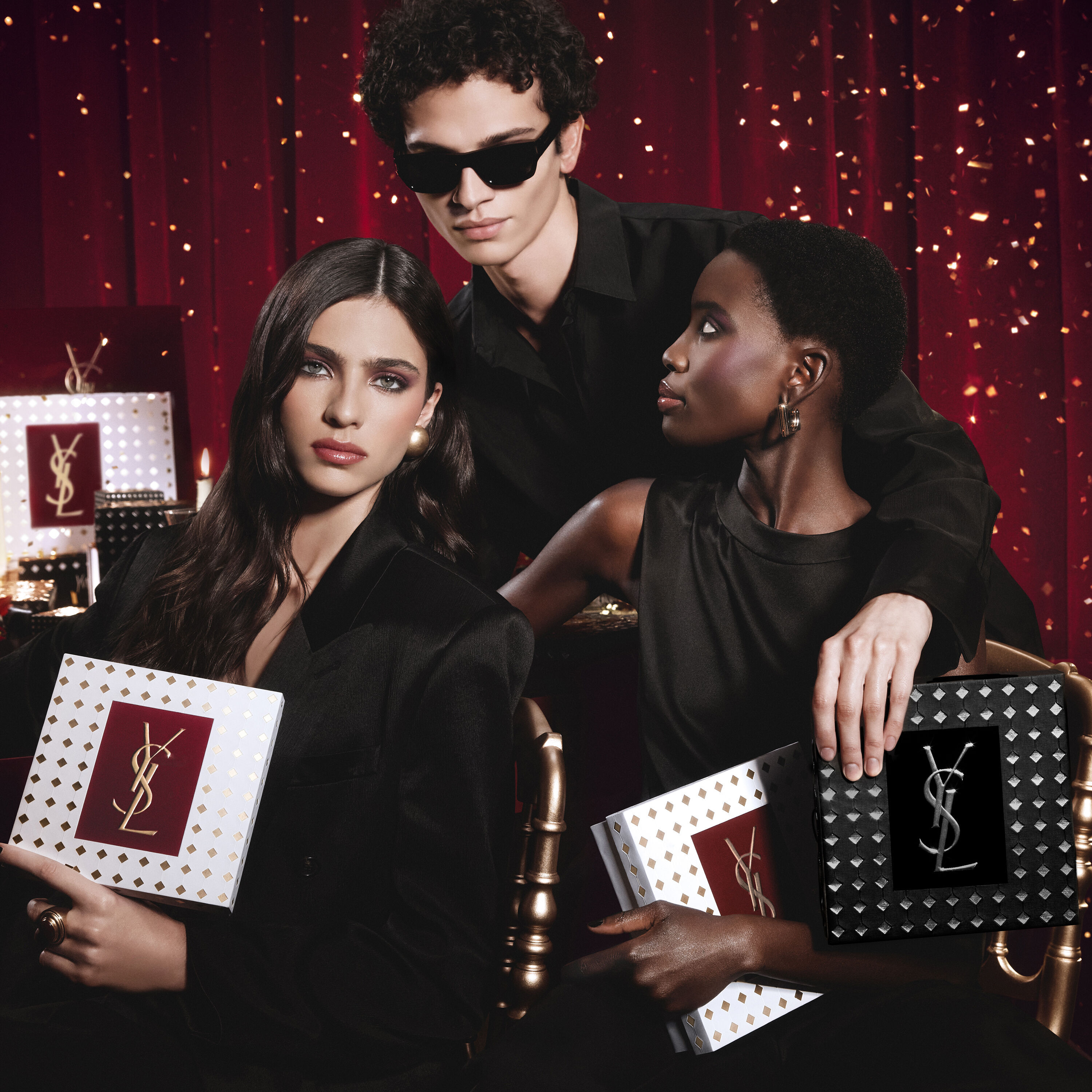 Modelle posieren gemeinsam, halten luxuriose YSL Holiday-Geschenkboxen in einer festlichen Atmosphare.