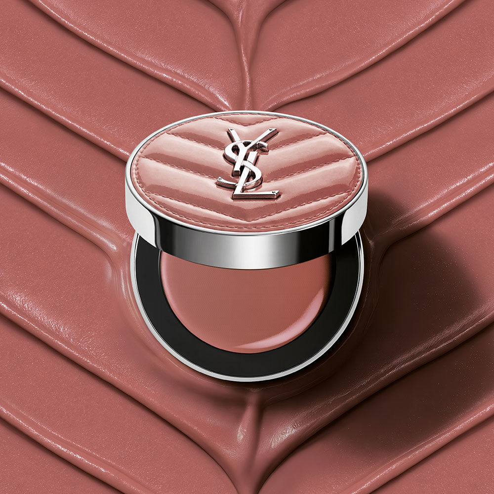 Ein offener YSL Make Me Blush Lifted Glow Cream Blush Kompakt in Nuance #44 Nude Lavalliere auf einem passenden pinkfarbenen, strukturierten Creme-Hintergrund.