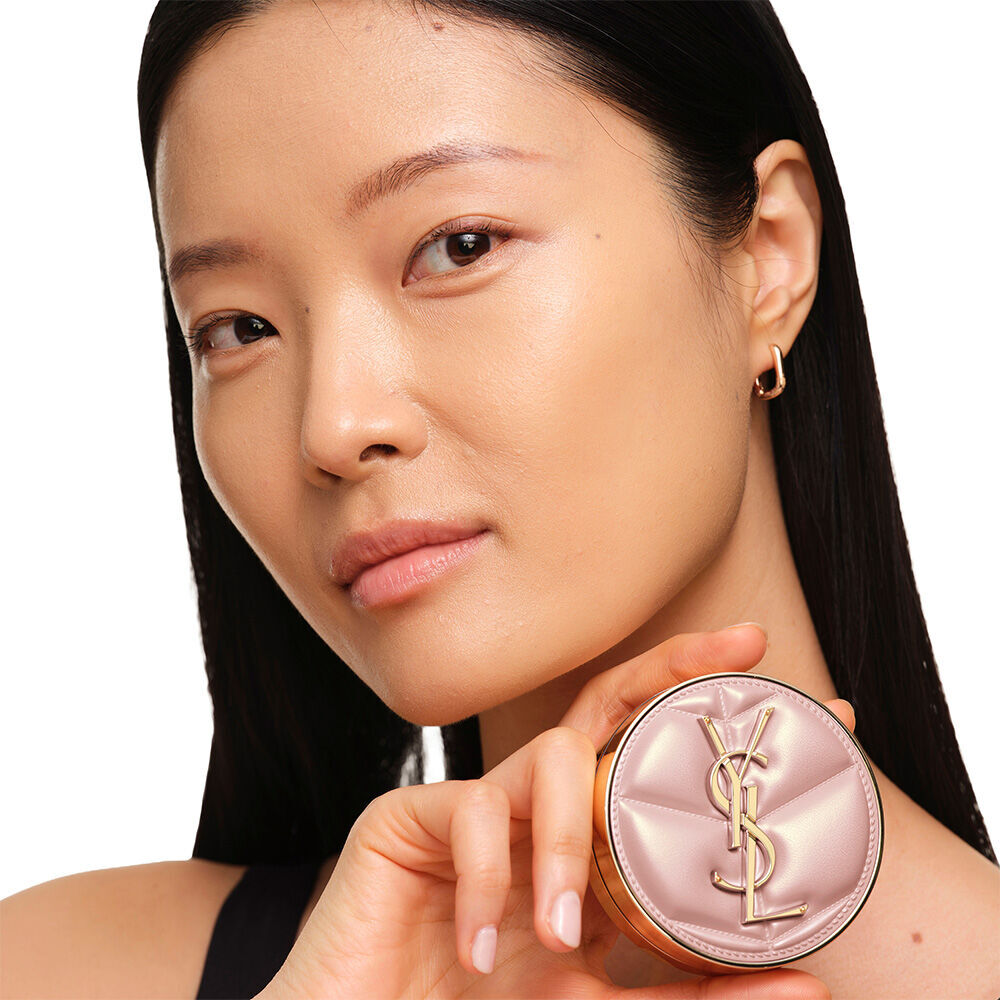 Model mit glatter, strahlender Haut, die das pinke YSL SKIN AFFAIR CUSHION FOUNDATION prasentiert, um einen naturlich leuchtenden, makellosen Haut-Look zu zeigen.