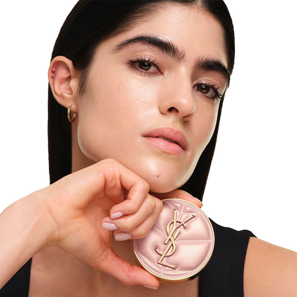 Model mit glatter, strahlender Haut halt das pinkfarbene YSL SKIN AFFAIR CUSHION FOUNDATION, um einen naturlich leuchtenden, makellosen Teint zu prasentieren.