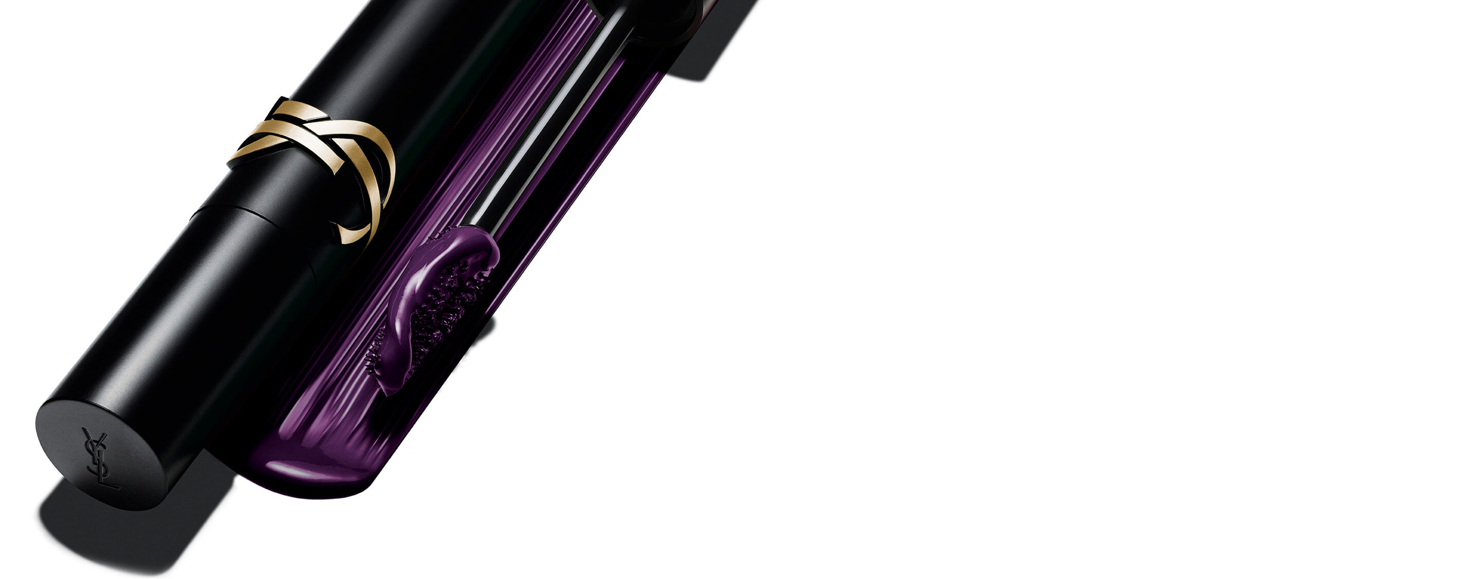 Yves Saint Laurent Lash Clash Mascara in Pflaume, mit schwarzer Hülse, goldenem YSL-Logo und der Bürste, die die lilafarbene Textur zeigt.