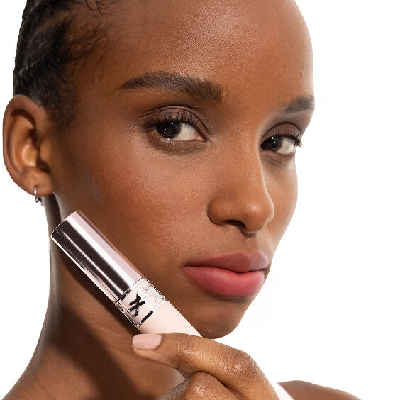 Model Zahara wearing YSL LOVENUDE Lip Blusher in Shade 7, holding the product near her rosy nude lips.