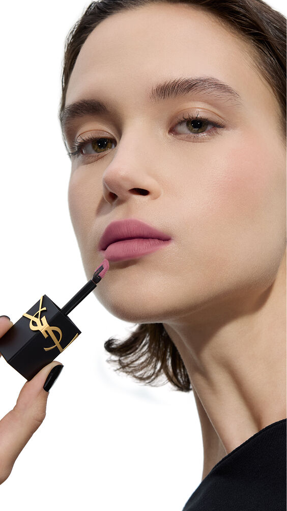 Modell mit hellem Hautton, das einen kühltonigen, zarten Mauveton von YSL THE INKS BLUR Lip Stain mit dem Applikator aufträgt.