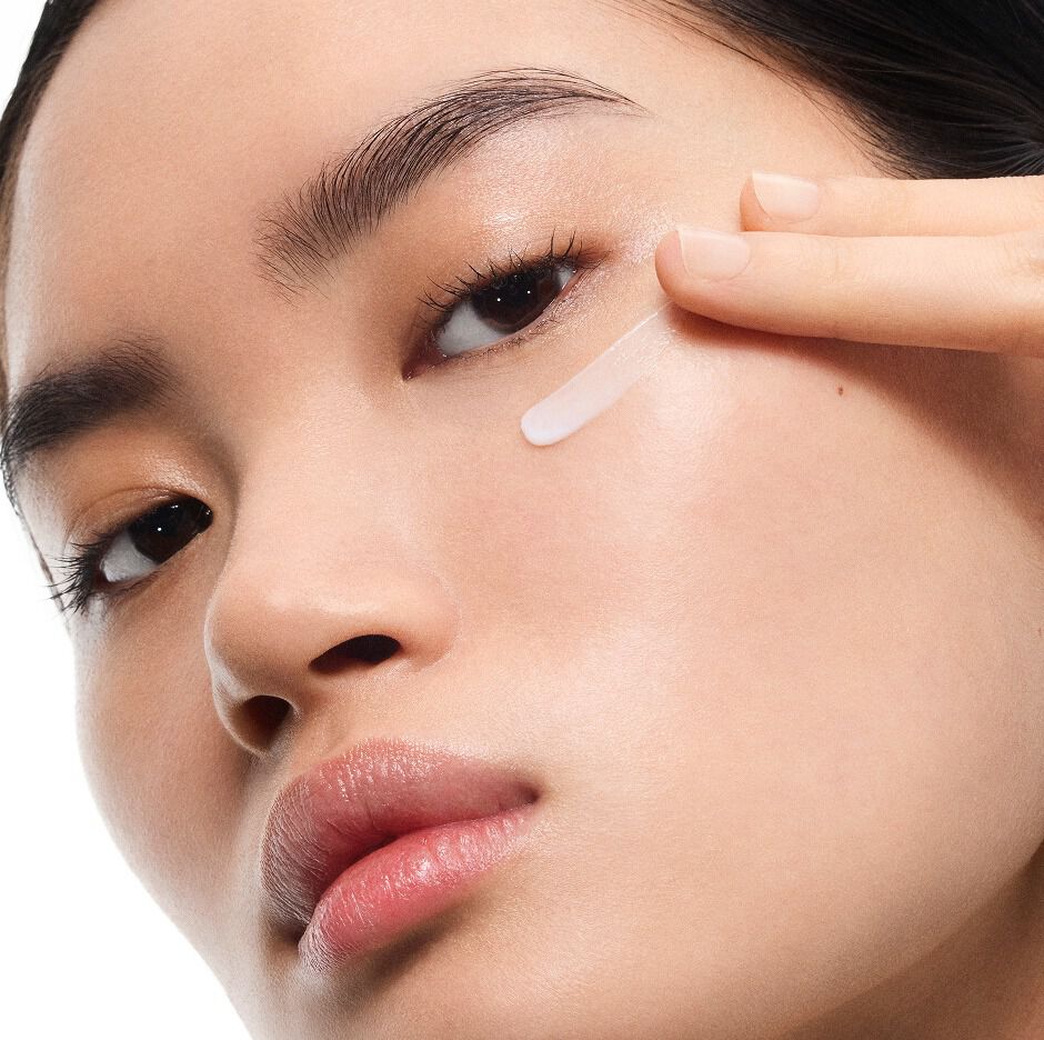 Mingma, mannequin au teint clair, appliquant la crème Eye Reboot Pure Shots d'YSL sous son œil, mettant en avant sa texture délicate.