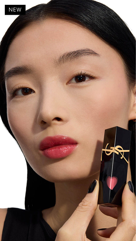 Modell mit hellem Hautton und einem glänzenden Beer-Rosa-Lippenlook, das die schwarze Flasche des YSL THE INKS VINYL CREAM Lip Stains mit dem glänzenden roten Herz hält.