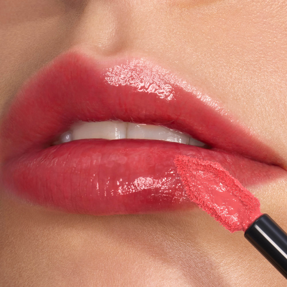 Nahaufnahme glänzender, hochglänzender Lippen, die mit dem angewinkelten, flach zulaufenden YSL Applikator präzise nachgezogen werden.