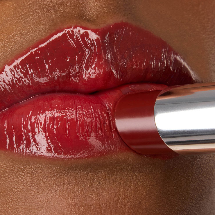 Nahaufnahme des YSL LOVESHINE Lippenstifts in der Nuance Berry Crush (Nr. 219), der auf die glänzenden, leuchtend roten Lippen von Model Zahara aufgetragen wird.