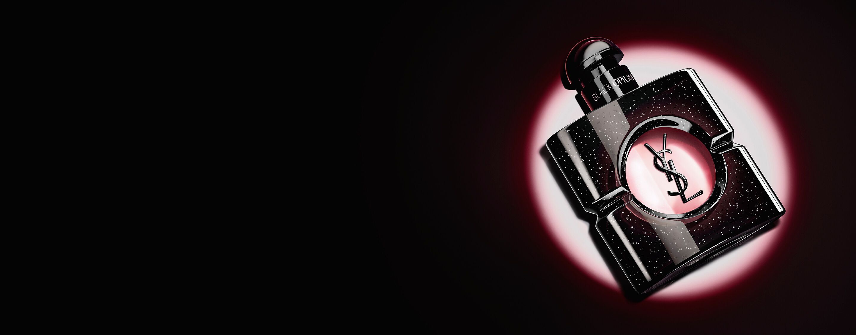 Flacon de Black Opium Eau de Parfum couché sur le côté sur une surface sombre, auréolé d’une lumière rose.