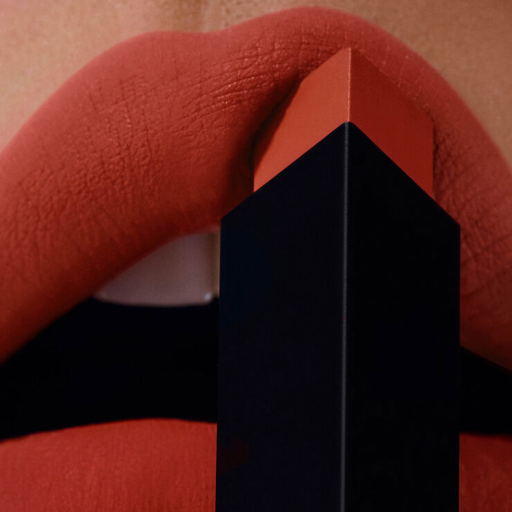 Étui YSL noir et or avec logo Cassandre sur fond doré.