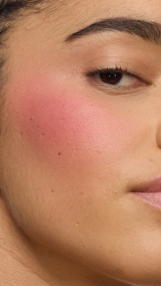 Gros plan sur la joue d’un modèle portant la routine Make Me Blush : Poudre #54 Berry Bang superposée à la Crème #44 Nude Lavallière pour un rose vibrant et sur mesure.